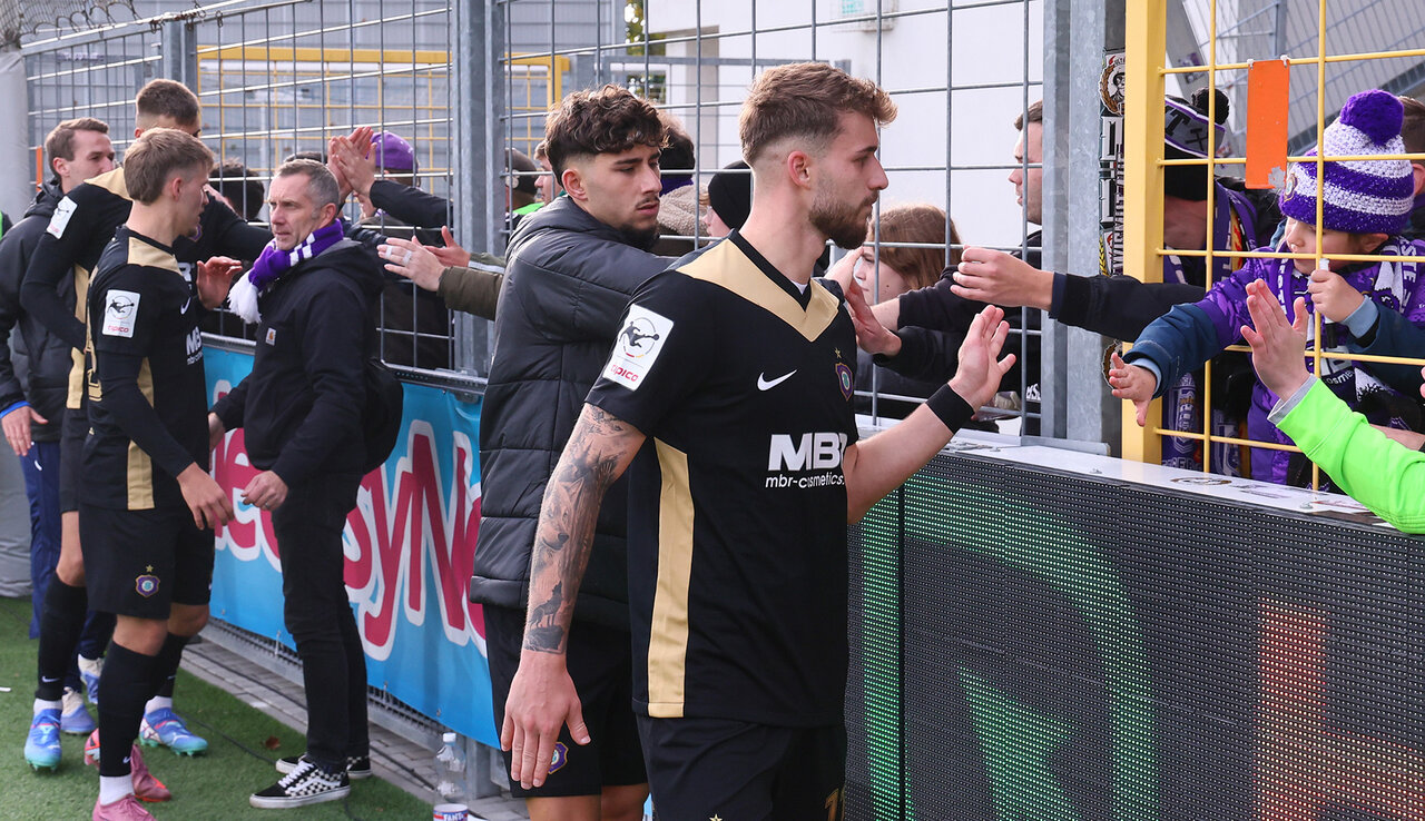 Mannschaft klatscht Fans am Zaun ab.